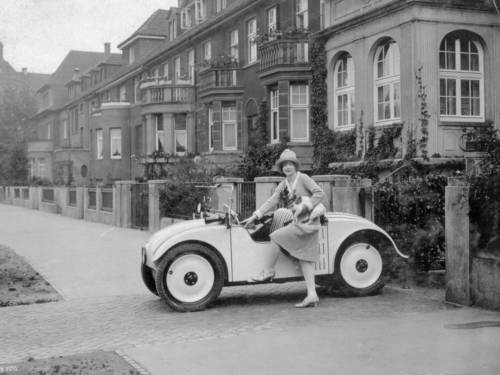 Werks-Foto der Fa. Hanomag, 2. Hälfte der 1920er Jahre: Frau mit Hund unter dem Arm steigt in einen Kleinwagen Hanomag-Kommissbrot.